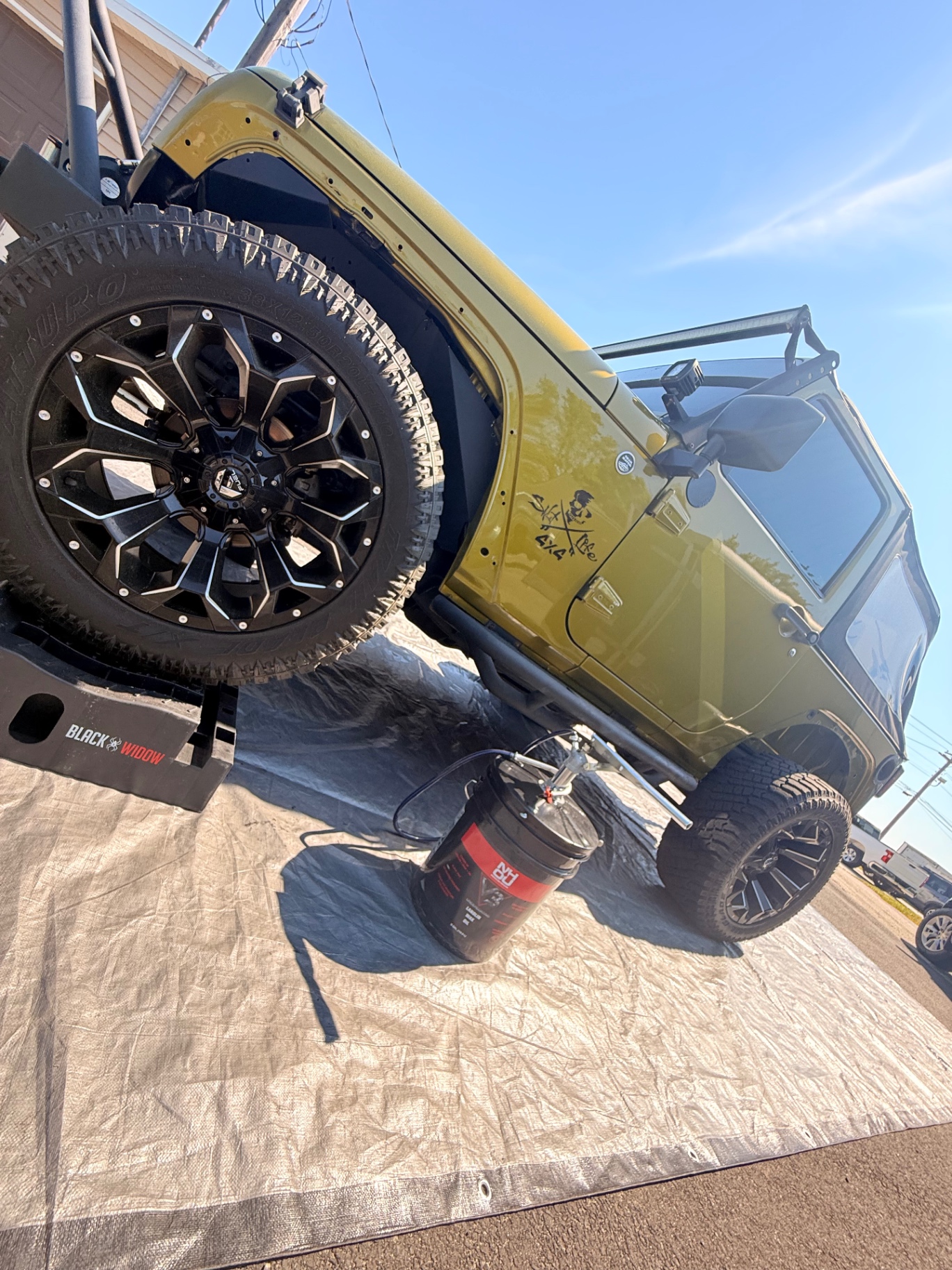 Lifted green Jeep Wrangler prepped for undercoating